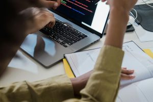 Two individuals discussing code on a laptop, focusing on web development.